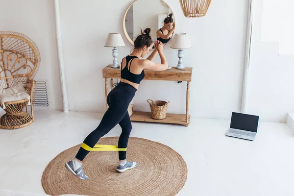 Vrouw aan het trainen thuis met elastische band — Stockfoto