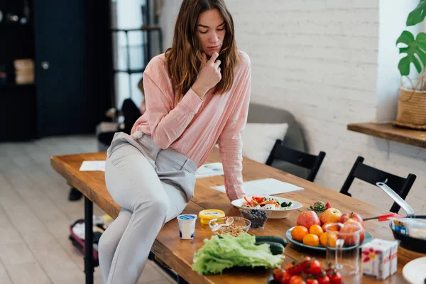 Mujer se sienta en la cocina y piensa en qué cocinar — Foto de Stock