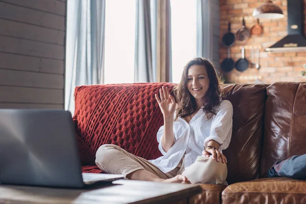 Woman at home waving as she makes video call on laptop computer. — ストック写真