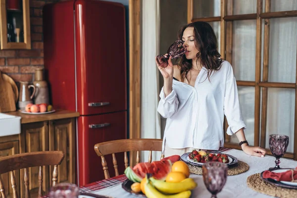 Young woman at home in the kitchen drinking water from glass — Photo