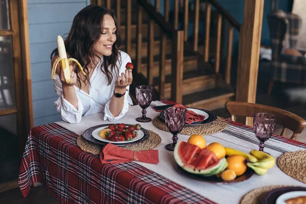 O tânără care mănâncă fructe în bucătărie — Fotografie, imagine de stoc