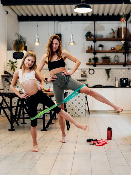 Anne ve kızı evde çalışıyor, bant egzersizi yapıyor. — Stok fotoğraf