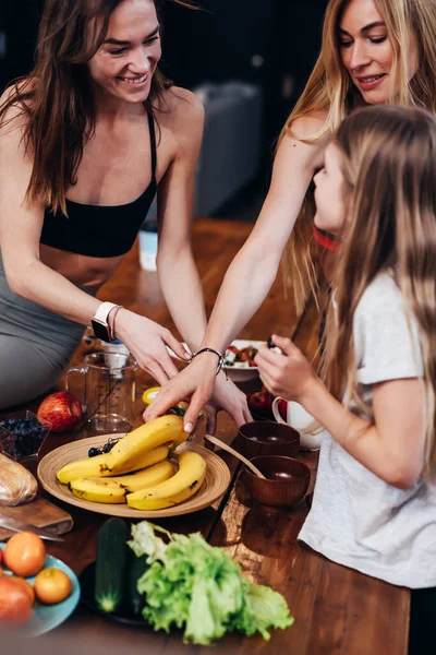 Mujeres jóvenes merendando fruta en la mesa de la cocina. — Foto de Stock