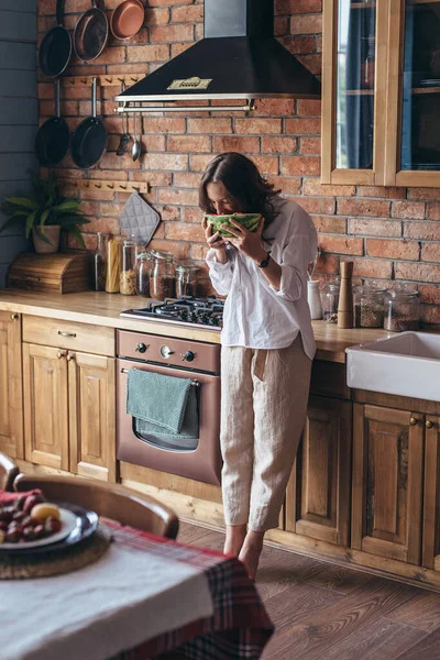 Frau zu Hause isst Wassermelone in der Küche — Stockfoto