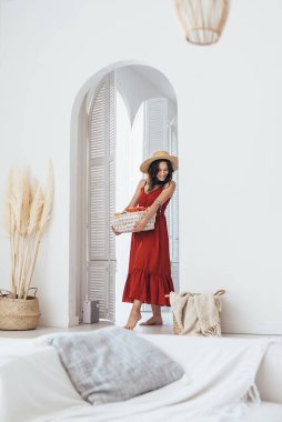 Genç bir kadın elinde meyve sepetiyle odaya giriyor.