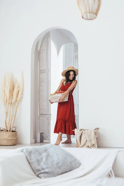 Mujer joven entra en la habitación con una cesta de frutas — Foto de Stock