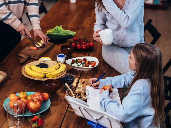 Hermanas cocinan y la más joven hace su tarea — Foto de Stock