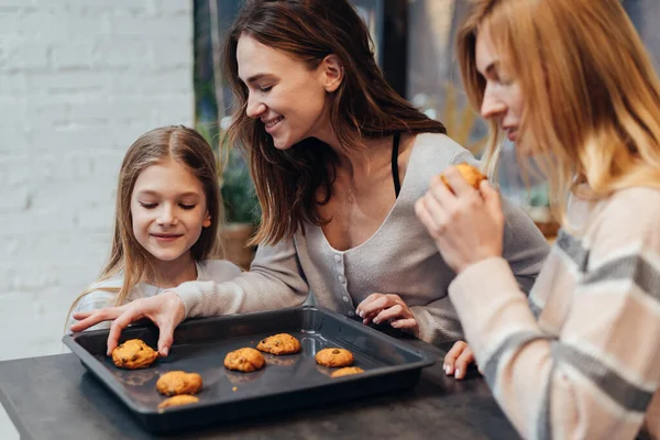 Ung kvinna och hennes vän är nyfikna på kakorna hennes dotter gjorde — Stockfoto