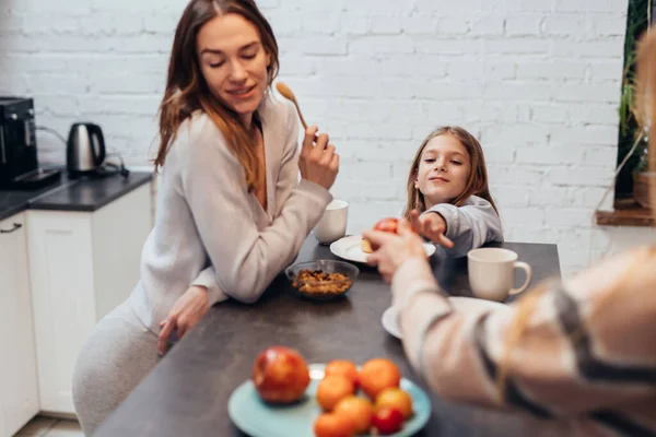 Dos mujeres jóvenes y una chica en la cocina cenando juntas — Foto de Stock