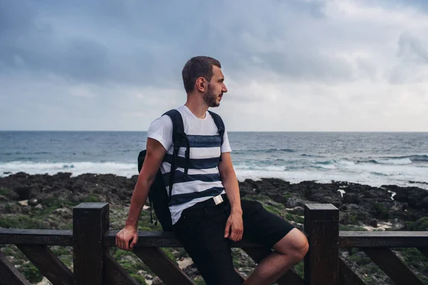 Jovem senta-se num corrimão junto ao mar — Fotografia de Stock