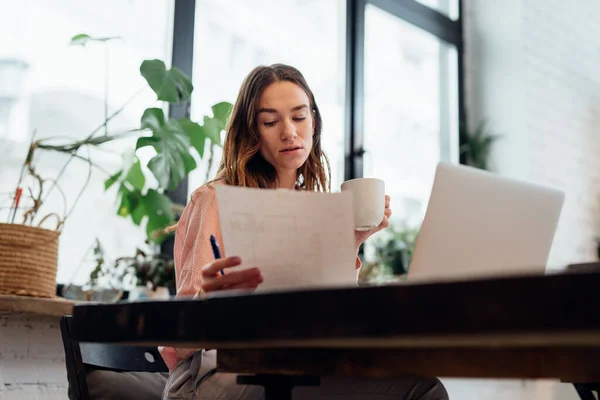 Ung kvinna studerar information vid middagsbordet — Stockfoto