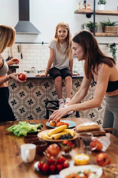 Idrottskvinna lagar mat, dukar bordet med rätter av frukt och grönsaker — Stockfoto