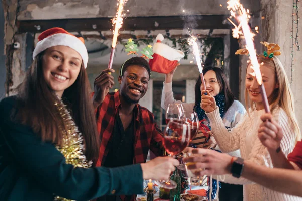 Amigos multi-étnicos a brindar vinho. Homens e mulheres jovens que fazem uma festa no café. Natal. — Fotografia de Stock