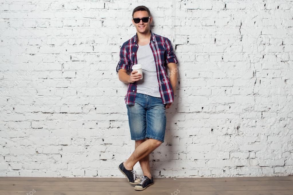 Bright young man hipster on vacation enjoying the day with coffee