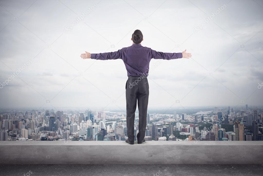 Confident businessman purple shirt and trausers standing on edge of roof with his hands sides front magnificent view city