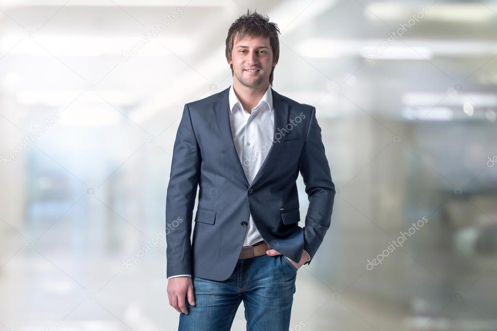 Handsome man in casual suit standing his office and smiling with a hand pocket