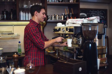 Genç yakışıklı barista hipster müvekkillerine kafede kahve yapım.