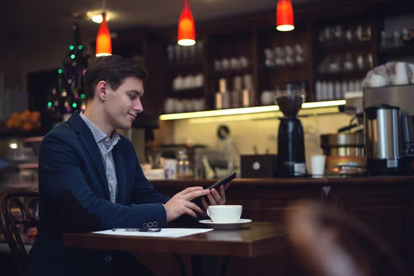 Jonge aantrekkelijke zakenman in een pak koffie drinken en het gebruik van Tablet PC om nieuws te lezen — Stockfoto