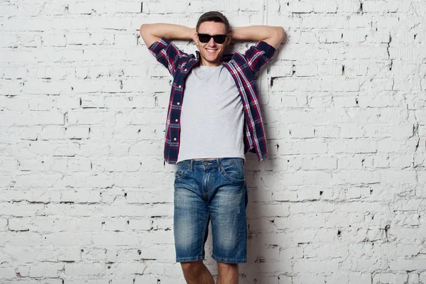 Young man in with sunglasses smiles happily hands behind head — Stock Photo, Image