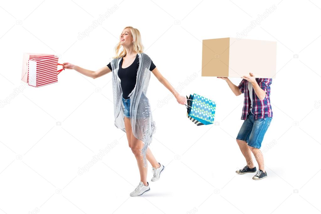 Young beautiful couple are going home after shopping with heavy boxes, gifts, goods.