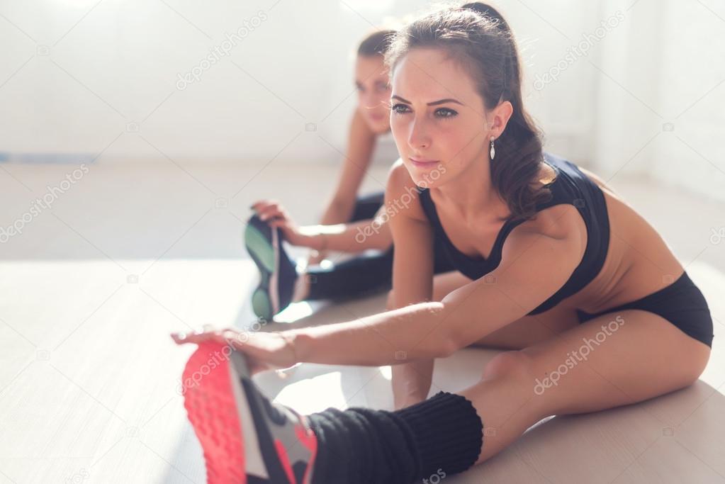 Group of fit women working stretching leg muscles back to warm up at gym fitness, sport, training and lifestyle concept.