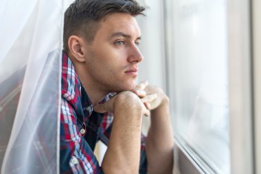 Handsome pensive man guy watching through the window concept sadness sorrow pain waiting clipart