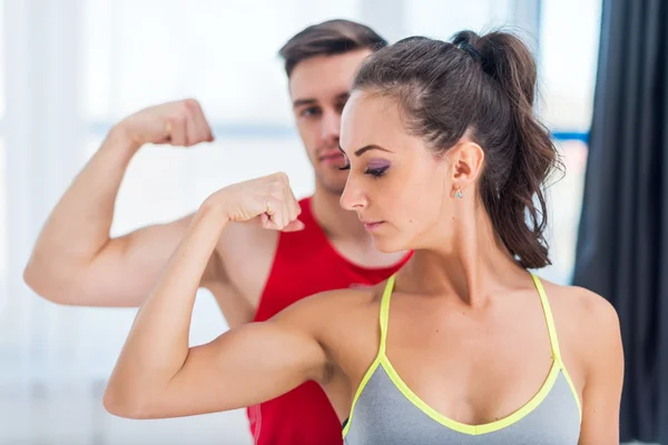 Aktiva athletic sportiga kvinnan flicka och man visar sina muskler biceps hälsosam livsstil — Stockfoto