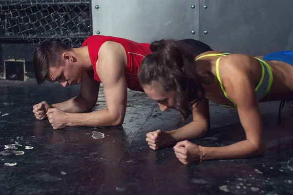 Ajuste deportivo hombre y mujer haciendo tablón núcleo ejercicio entrenamiento espalda prensa músculos concepto gimnasio deporte deportista crossfit fitness entrenamiento fuerza potencia —  Fotos de Stock