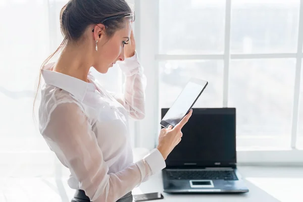 Businesswoman staring at the tablet in front of window office — Stock Photo, Image