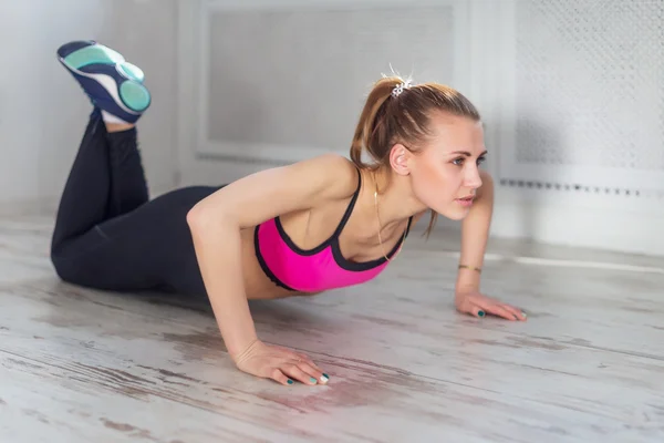 Fitness atleet sportieve vrouw sport model meisje opleiding crossfit doet push ups thuis — Stockfoto