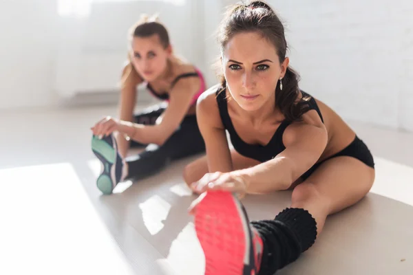 Groupe de femmes en forme qui travaillent en étirant les muscles de leurs jambes pour se réchauffer à la salle de fitness, au sport, à l'entraînement et au mode de vie . — Photo