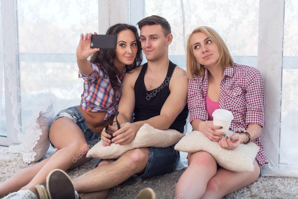 two girls and guy friends taking selfie together wearing summer clothes  jeans shorts jeanswear street urban casual style having fun at home