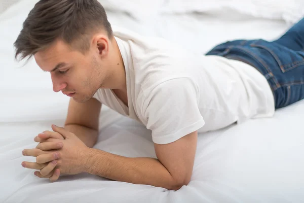Bra letar man i vit T-shirt och Blå jeans liggande på hans säng hemma — Stockfoto