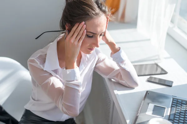 Porträtt av trött ung affärskvinna lider av huvudvärk framför laptop på kontoret skrivbordet — Stockfoto