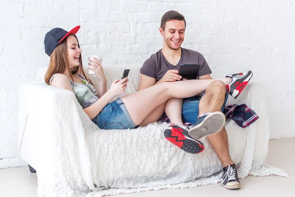 Jonge vrienden grappige jongens actieve mensen veel plezier samen zitten op de bank verzenden bericht chatten met behulp van app gaming met hun smartphones thuis concept sociale media — Stockfoto