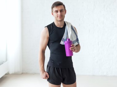 Havlu ve kokteyl shaker protein ya da şişe su ile tutarak sporcu yaptıktan atletik bir adam portresi egzersizleri.