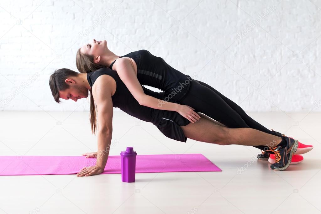 Man doing push ups with woman laying on back at gym or home