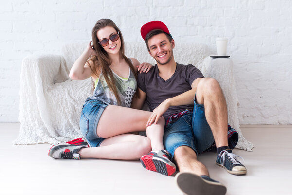 Friends girl and guy sitting on floor at home in summer jeanswear street urban casual style talking, having fun