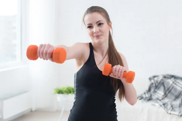 Actieve sportieve atletische vrouw boksen halters oppompen van spieren naar camera in lichte kamer concept fitness sport opleiding levensstijl — Stockfoto