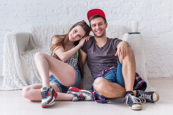 Friends girl and boy sitting on floor at home in summer jeanswear street urban casual style talking, having fun