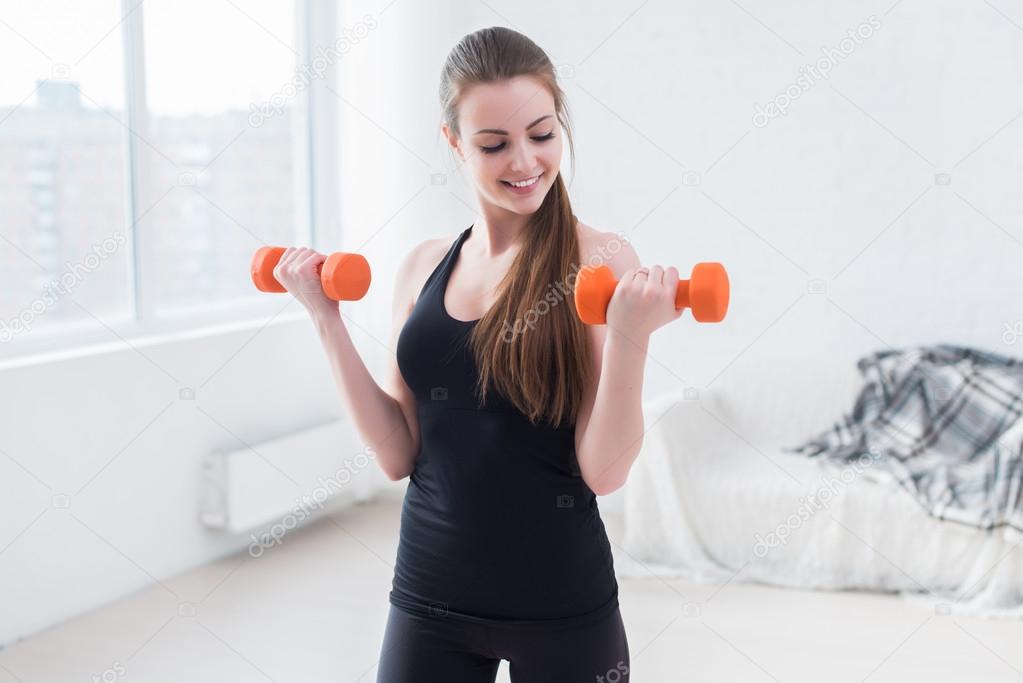 Active sportive athletic woman with dumbbells pumping up muscles biceps concept fitness sport training lifestyle.