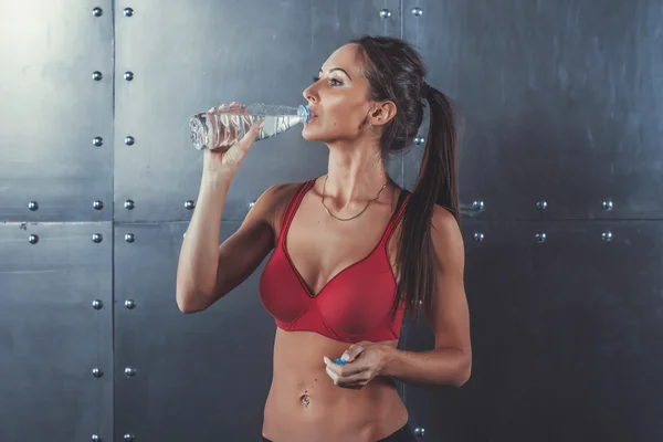 Svalnatý sportovní sportovec žena pitné vody v tělocvičně po cvičení cvičit fitness, sport, vzdělávání a životním stylu koncepce. — Stock fotografie