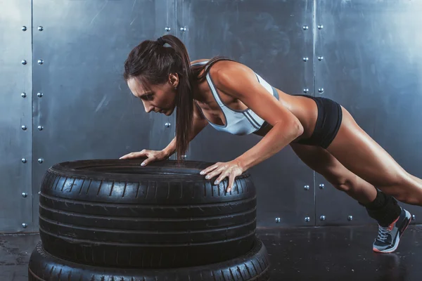 Desportista. Ajuste a mulher desportiva fazendo flexões no conceito de treinamento de força de pneu crossfit fitness treino esporte e estilo de vida . — Fotografia de Stock