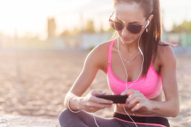 Oturma ve smartphone vasıl sonra egzersiz doğa dışarıda portre yaz akşam arıyorsunuz müzik dinleme dinlenme yorgun kadın.