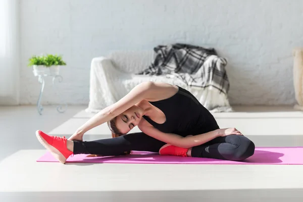 Fit vrouw hoog lichaam flexibiliteit stretching haar been en terug naar opwarmen doen aerobics gymnastiek oefeningen thuis — Stockfoto