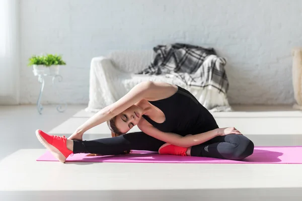 Passar kvinnan hög kropp flexibilitet stretching hennes ben och rygg att värma upp göra aerobics gymnastik övningar hemma — Stockfoto