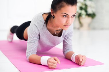 Pretty young woman doing plank abdominal exercise at home in white room concept healthy lifestyle sport fitness