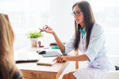 Medical physician doctor woman talking to patient sitting by the table.