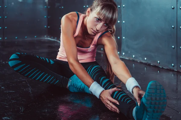 Mujer en forma haciendo ejercicios de estiramiento sus músculos espalda y piernas antes de un entrenamiento de calentamiento en el gimnasio concepto de fitness, deporte, estilo de vida . —  Fotos de Stock