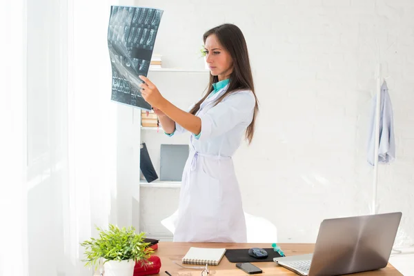 Ung kvinna läkare tittar på en patient röntgen på sjukhuset. — Stockfoto